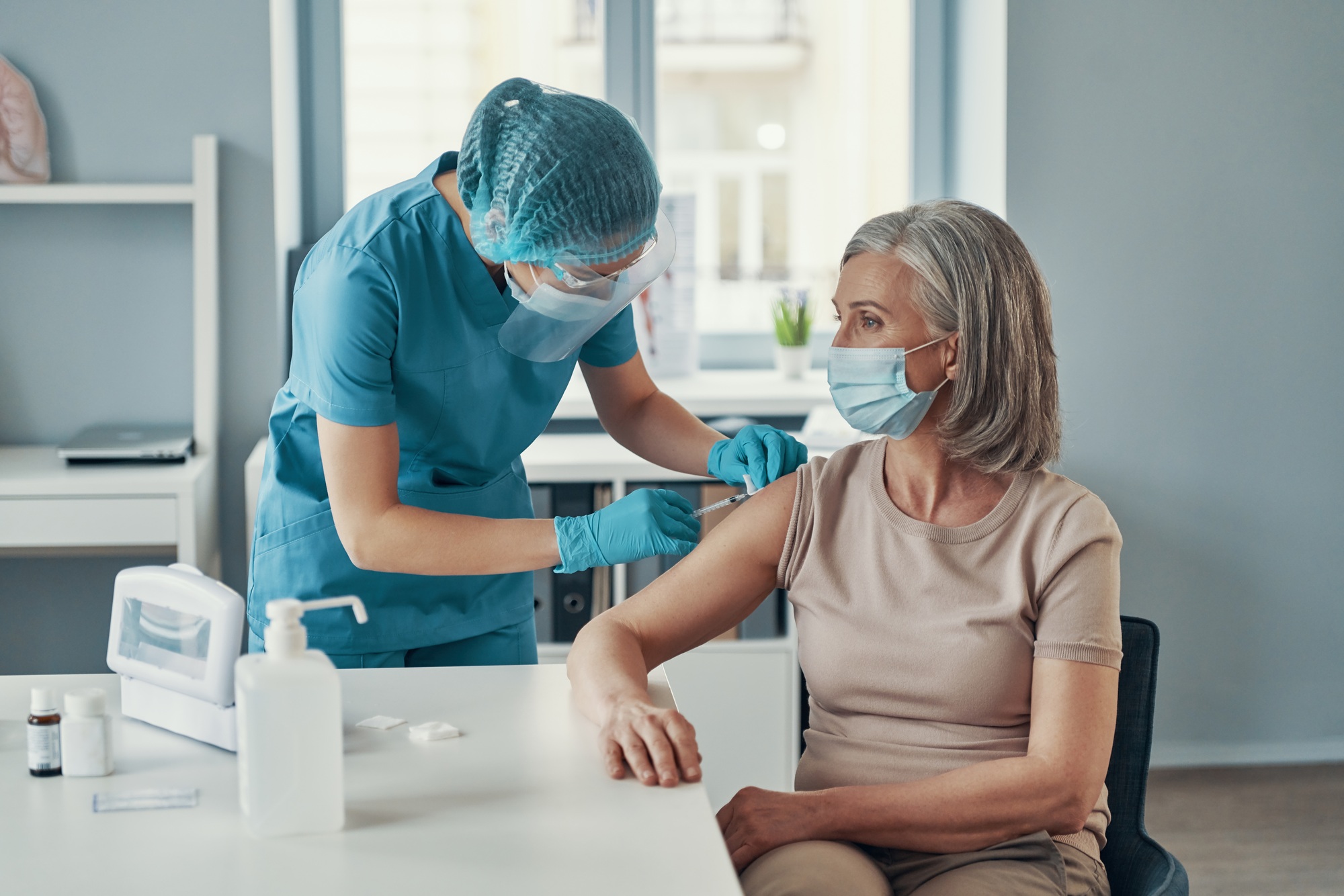 Female nurse making injection to mature woman while working in the hospital