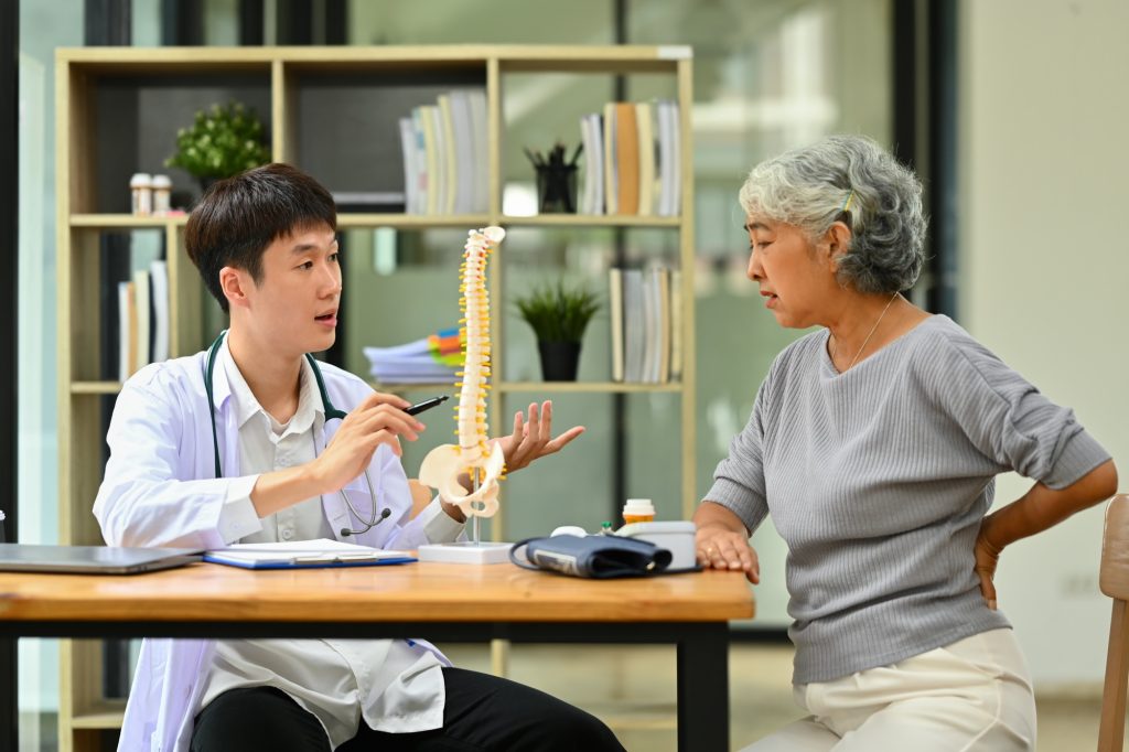 Orthopedist giving consultation about scoliosis or spinal problems to patient.